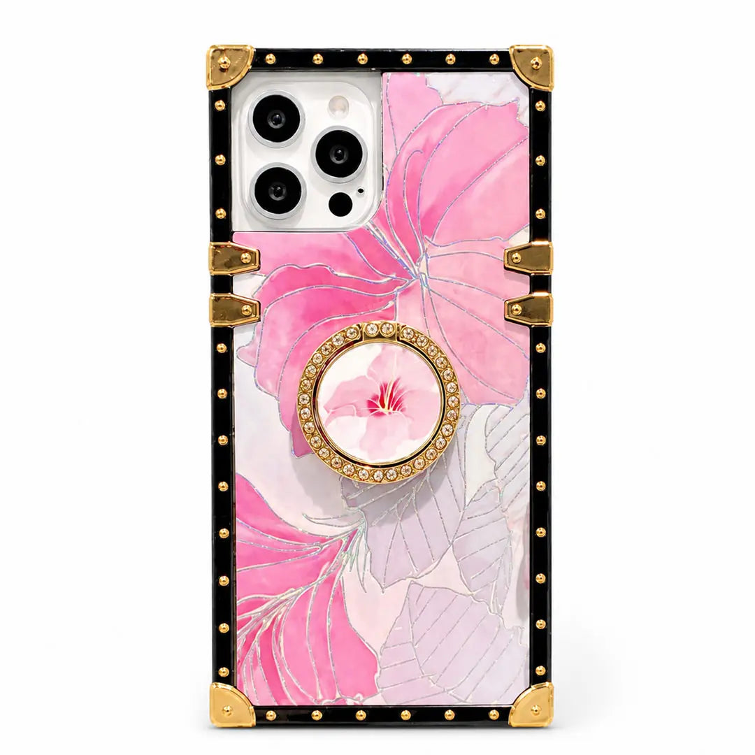 A protective phone case with a pink hibiscus floral print, featuring a black border with gold rivets and corner protectors, a gold-trimmed circular ring, and a central pink flower accent.