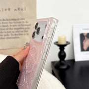 Phone case with glittery pink design held by a hand, blurred background