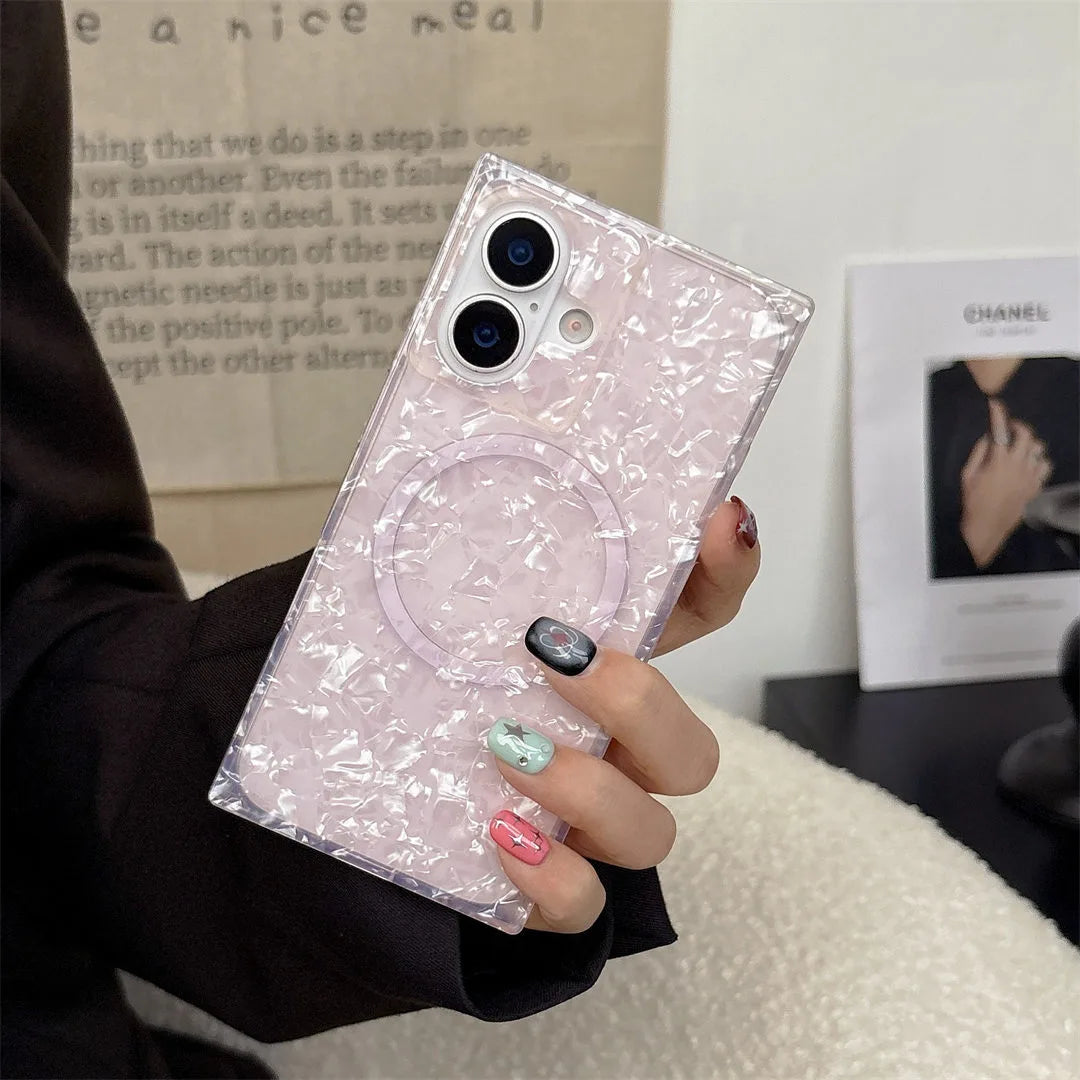 Person holding a phone with an opal shell print case in front of a magazine