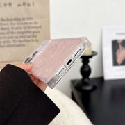 Phone case with pink glittery design held by a hand against a blurred indoor background