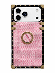 A pink textured fabric phone case with a black leather border, gold-tone metal studs, corner protectors, and a central circular ring holder, shown on a white phone.