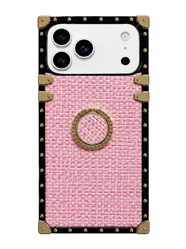A pink textured fabric phone case with a black leather border, gold-tone metal studs, corner protectors, and a central circular ring holder, shown on a white phone.