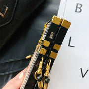 Gold and black phone case held by a hand with a blurred background