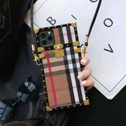 square Phone case with plaid design and gold accents held by a hand, with sunglasses and a white card in the background.