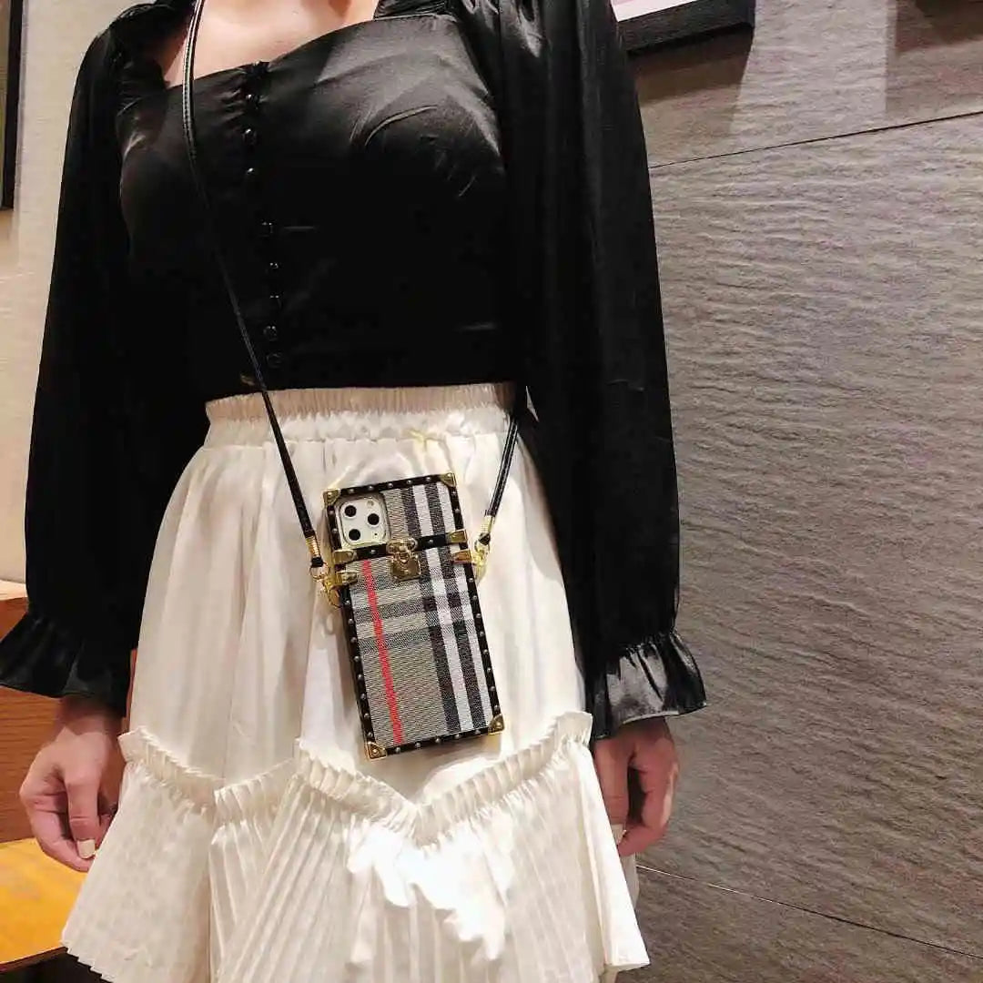 Person wearing a black top and white skirt with a phone case featuring a plaid design.