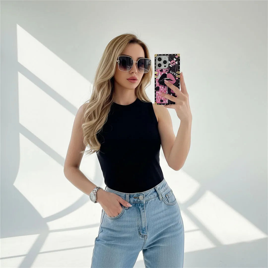 Woman taking a mirror selfie wearing sunglasses and holding a phone with a colorful case.