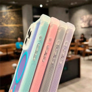 Four phone cases in pastel colors held up in front of a blurred indoor background