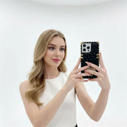 Woman holding a smartphone with a black and gold case against a white background