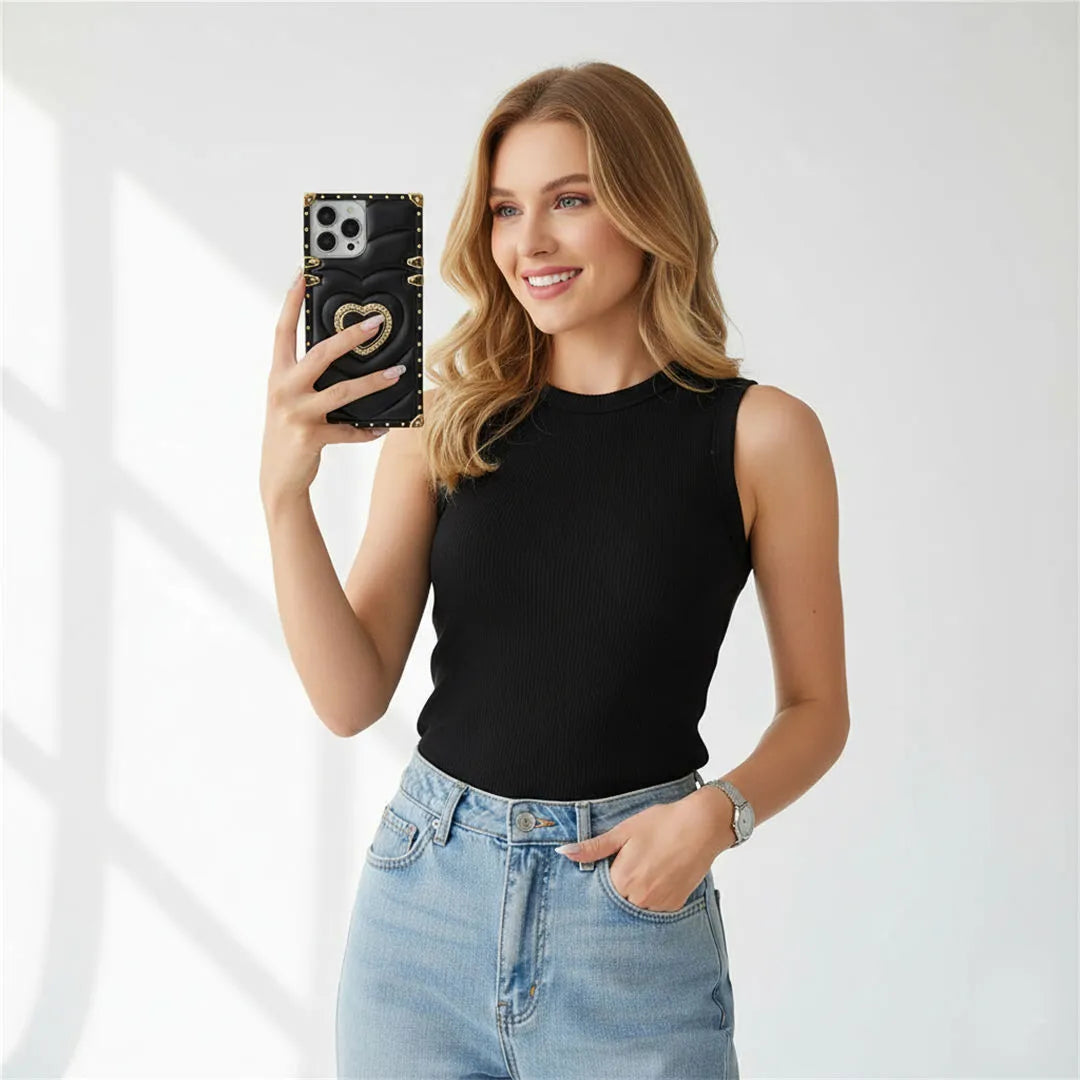 a woman is holding a phone in black square phone case with heart-shaped ring holder