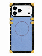 A protective phone case with a light blue textured backplate, a black border, and gold-tone metal corner protectors and rivets. The case features a faint circular graphic in the center and is shown fitted on a white smartphone.