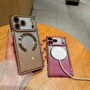 Two sparkly phone cases with rhinestone trim are shown on a wooden table. One case is held in a hand and is champagne gold with a gold magnetic ring, while the other is pink with a white MagSafe ring and a charging cable attached.