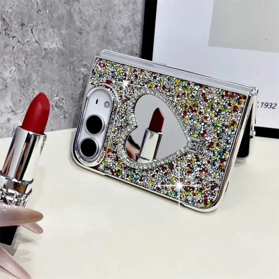 A silver glitter flip phone case with a heart-shaped mirror, styled on a white surface with a red lipstick in the foreground.