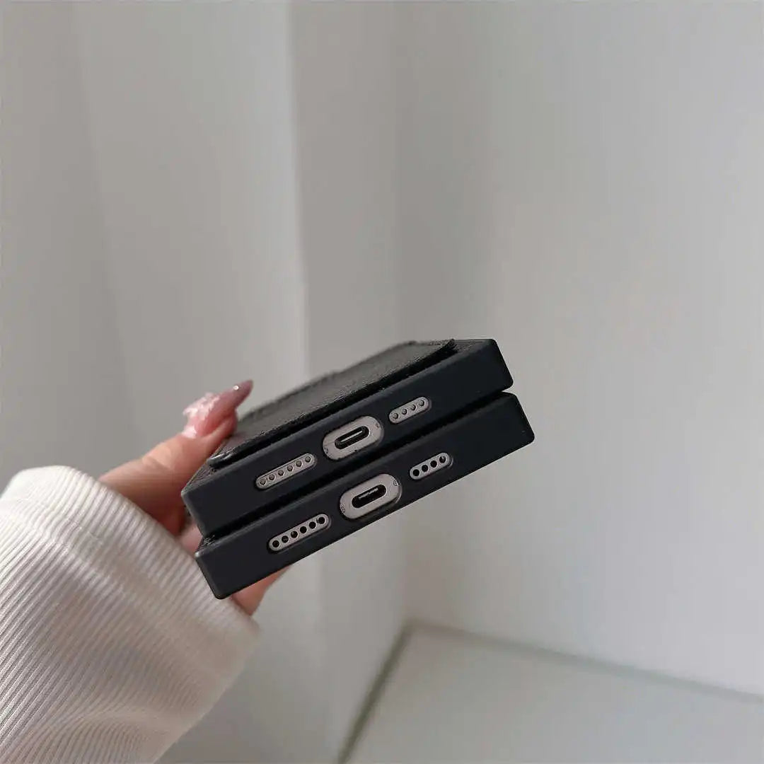 Bottom view of two Noir Card Square iPhone cases showing charging-port and speaker cutouts