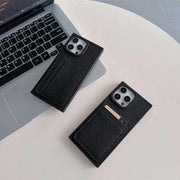 Two black Noir Card Square iPhone wallet cases beside a laptop, with a card tucked into one case
