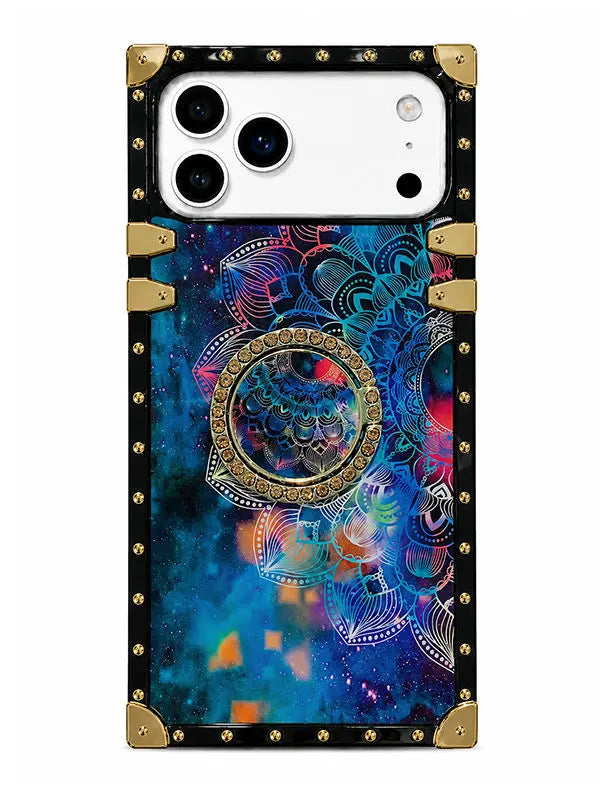 A protective phone case with a black border, gold-tone metal corner guards and rivets, and a vibrant cosmic mandala print featuring blue, purple, and pink tones on a white phone back.