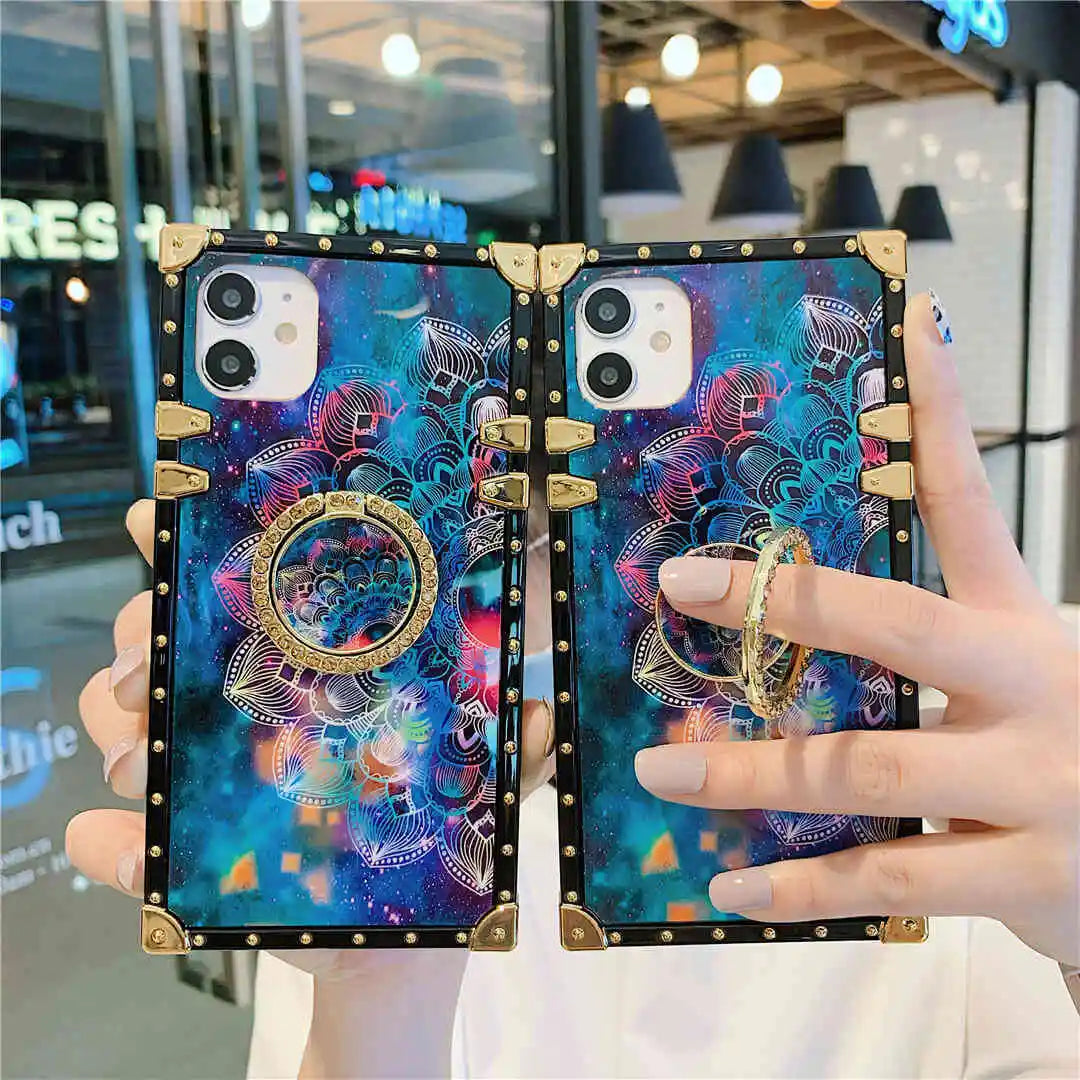 Two mandala print phone cases with a colorful design held by a person in front of a store.
