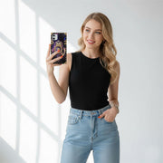 Woman taking a selfie wearing a black sleeveless top and blue jeans in a bright room.