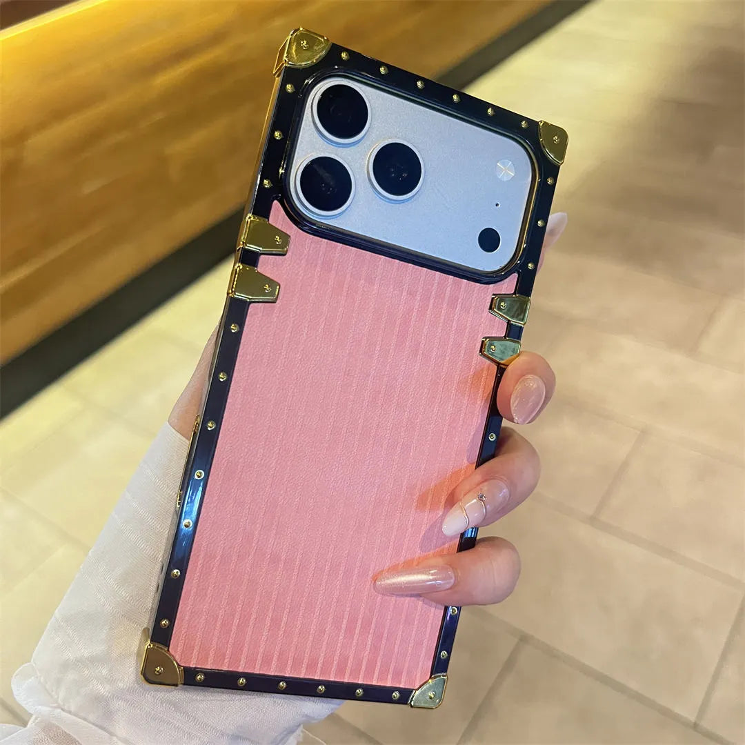 Phone case with pink back and gold accents held by a hand
