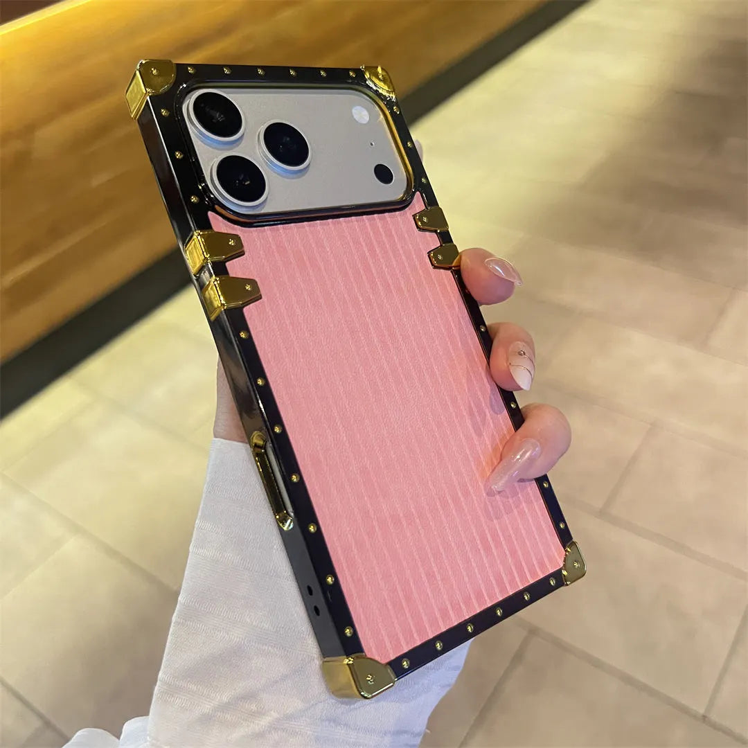Phone case with pink back and gold accents held by a person.