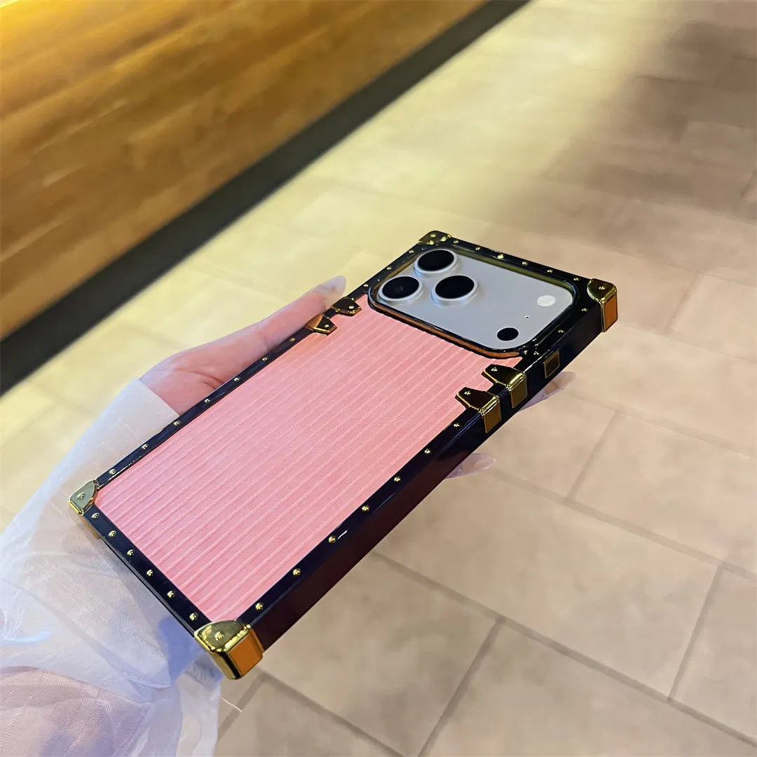 Phone case with pink interior and gold accents held by a hand on a tiled floor.