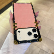 Phone case with gold accents held by a hand on a light background