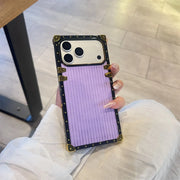 Phone case with a purple design held by a person on a light wooden floor.
