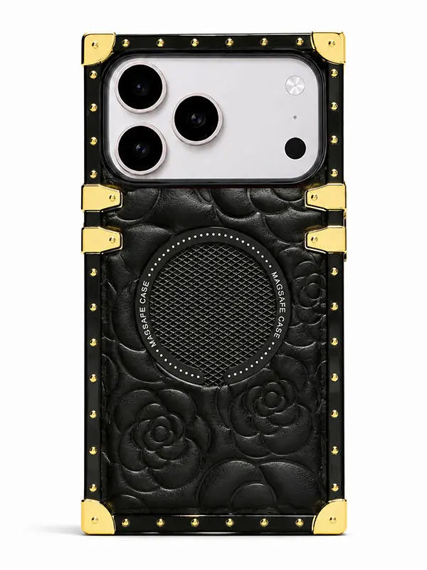 A black embossed leather phone case with gold-tone metal corner protectors and rivets, featuring a circular speaker grille and a large camera cutout, shown on a white background.