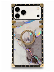 A protective phone case with a black and gold riveted frame, featuring a white and gray marble pattern with iridescent accents and a central gold circular ring stand.