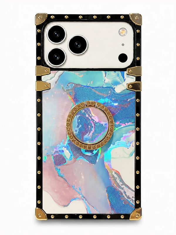 A protective phone case with a black border, gold-tone rivets and corner guards, featuring a holographic marble pattern in shades of blue, pink, and purple, with a built-in gold circular ring stand in the center.