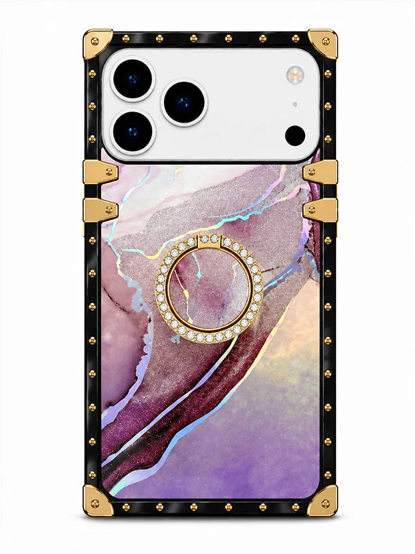 A protective phone case with a black frame featuring gold-tone rivets and corner protectors, a purple and pink marble pattern back, and an integrated circular ring stand embellished with small clear rhinestones.