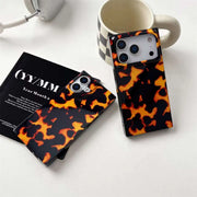 Two tortoiseshell patterned phone cases on a white surface with a magazine and mug.