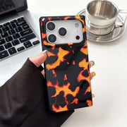 Phone case with tortoiseshell pattern held by a hand on a desk with a laptop and coffee cup.