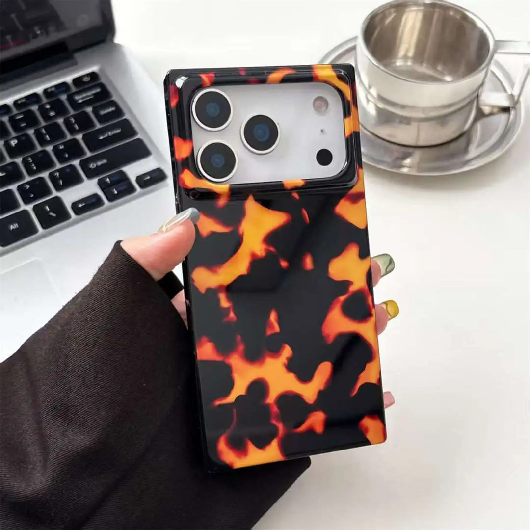 Phone case with tortoiseshell pattern held by a hand on a desk with a laptop and coffee cup.