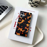 Phone case with tortoiseshell pattern on a book with a laptop and mug in the background