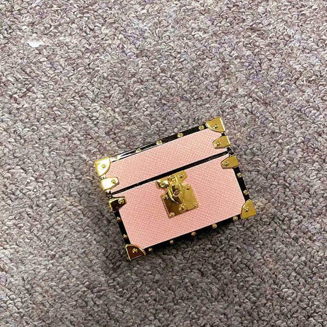 pink Vintage Luggage AirPods Cover with gold accents on a textured surface