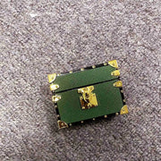 Green Square AirPods Case with gold accents on a gray carpet