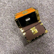 Two Shockproof square AirPods Pro protectors with gold accents on a textured gray surface