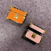 Two small Unique AirPods Pro case gifts, one orange and one pink, with gold accents on a textured surface.