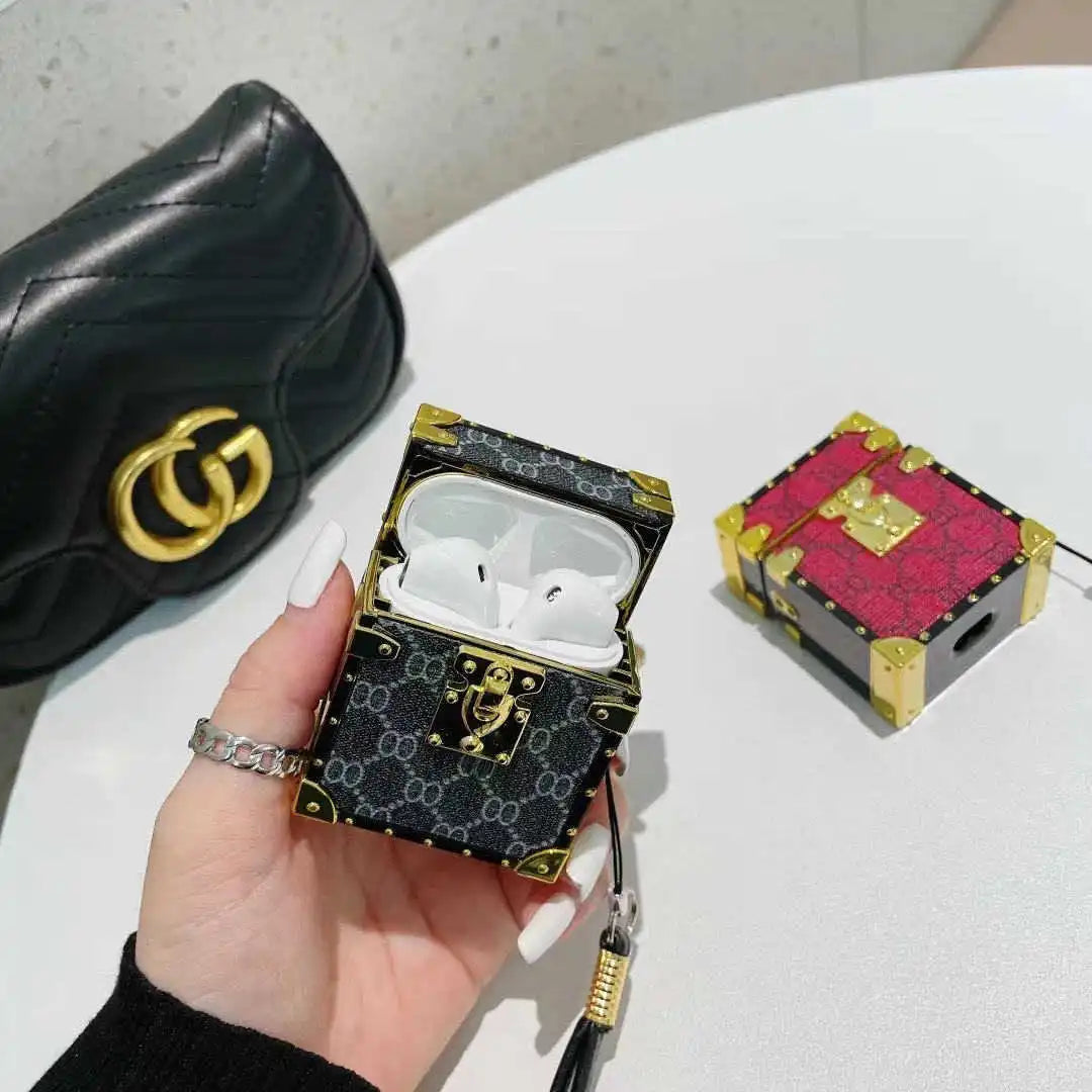 Black Gucci-patterned airpod case held by a hand with a white background