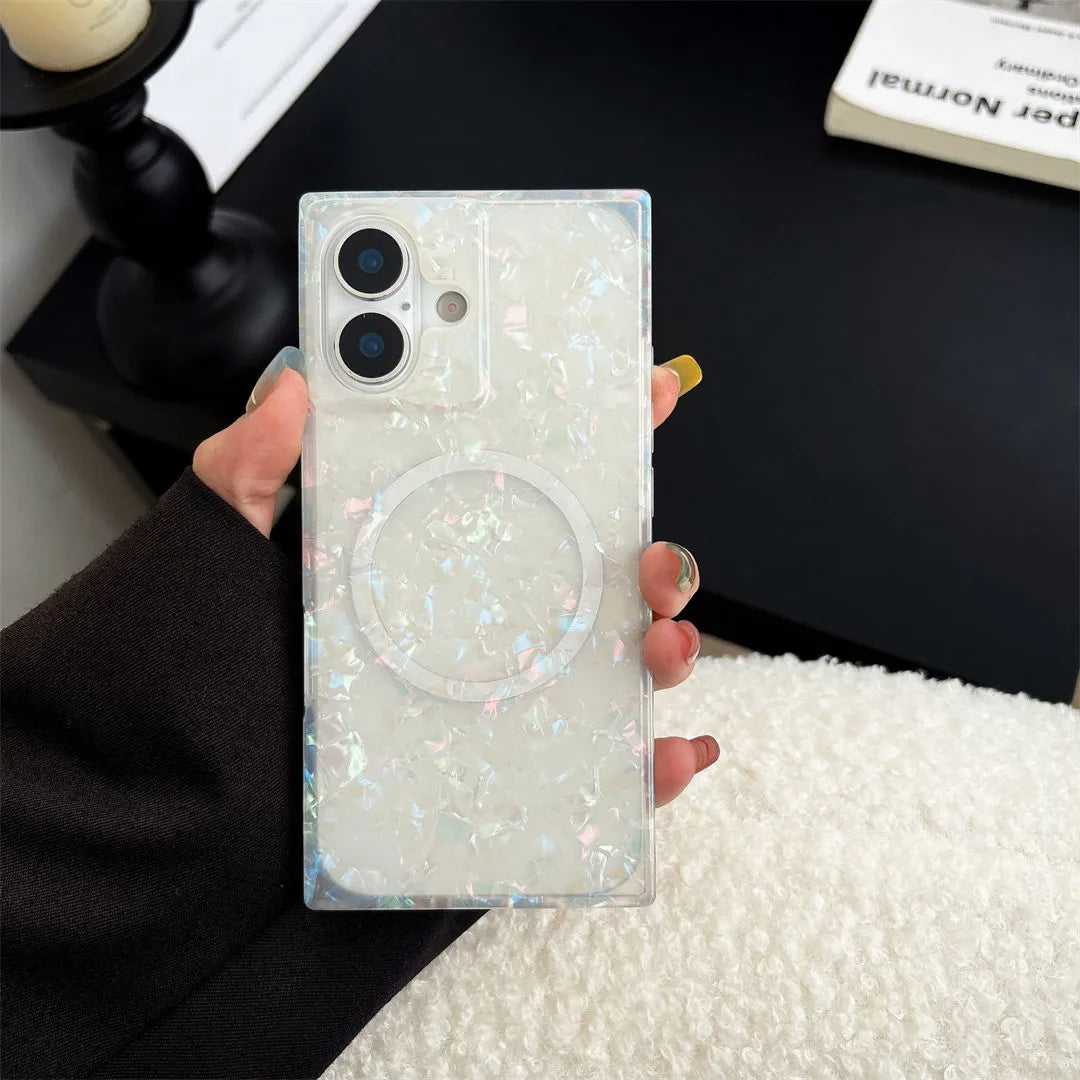 Person holding a phone with a glittery case on a blurred indoor background