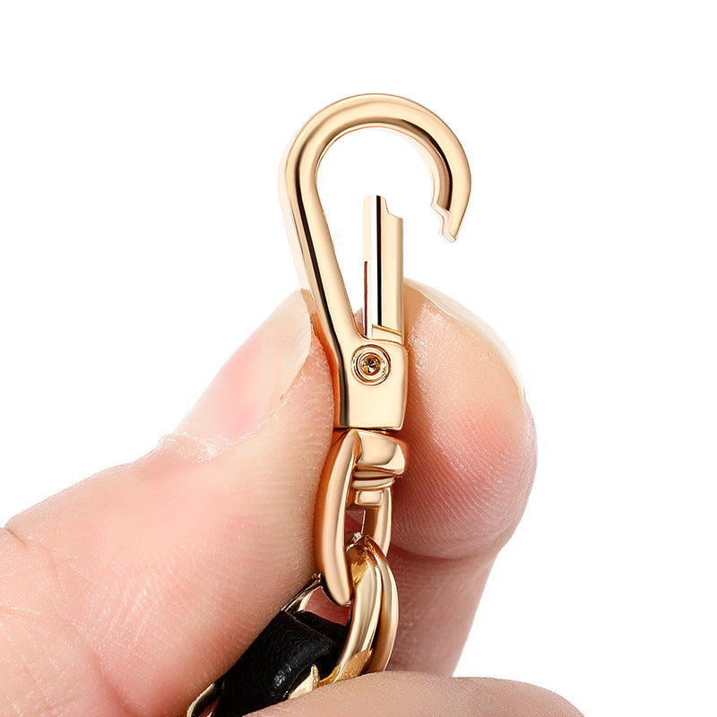 Gold carabiner held between fingers against a white background